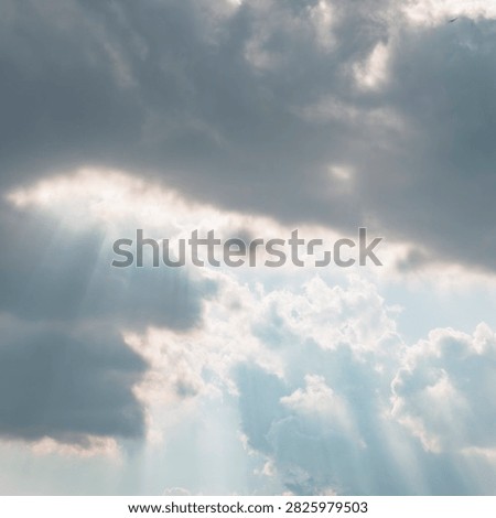 Sun rays breaking through dramatic storm clouds in a blue sky. Crepuscular rays, sunlight beam skyscape background.
