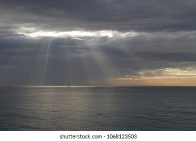 Sun rays breaking through the storm clouds over the sea. 