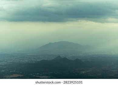 Sun Rays Breaking Through Storm Clouds Over Mountain Landscape
