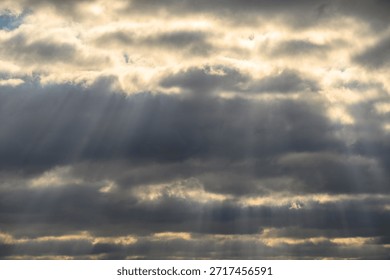 Sun rays breaking through thick clouds in a dramatic sky.