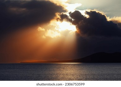 Sun rays and dark clouds over the ocean . Dramatic Sky with Awesome Clouds over the Island