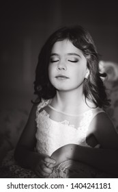 Sun rays fall on the face of little girl. Beautiful little model in studio with natural light