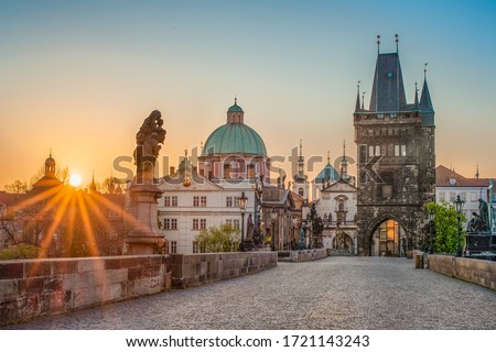 Sun rays filling the scene with colors during sunrise on empty deserted Charles bridge in Prague, Czech Republic
