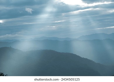 Sun rays filter through the clouds in hills of the valley illuminated by the sun's rays filtering through the clouds