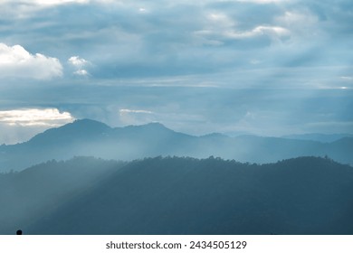Sun rays filter through the clouds in hills of the valley illuminated by the sun's rays filtering through the clouds