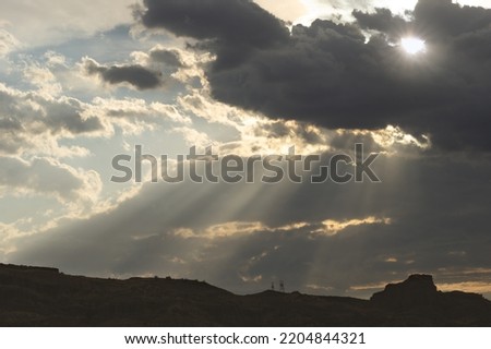 Sun rays flitering through sunset clouds shown in the Mojave Desert, California, United States.