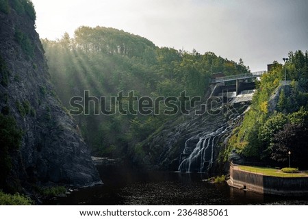 Sun rays and fog at hydro power plant, Waterfall Park, Riviere-du-Loup, Quebec, Canada. Photo taken in September 2023.