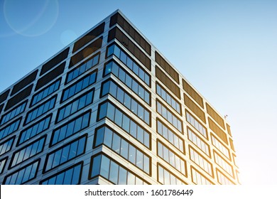 Sun rays light effects on urban buildings in sunset. Modern office building detail, glass surface with sunlight. Business background. 