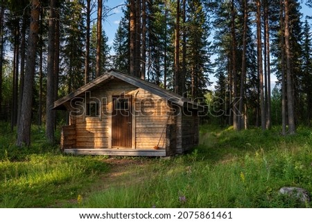 Sun rays on Log Cabin along Hiking Trail in the Woods for Protection from bad weather or in need for warmth or tired legs.