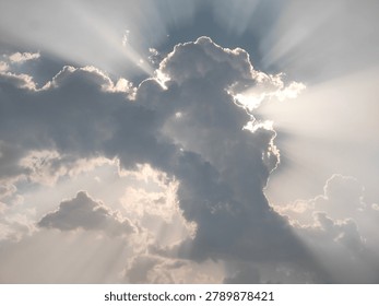 Sun rays piercing through thick clouds over sky.