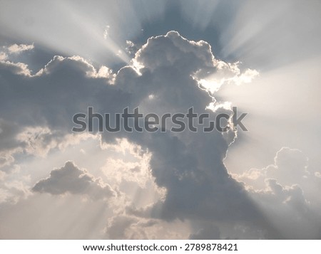 Sun rays piercing through thick clouds over sky.