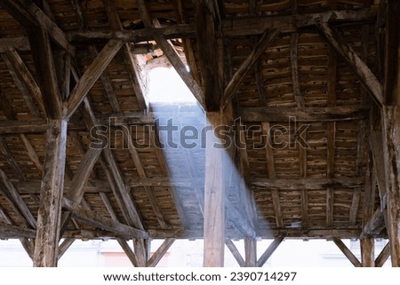 Sun rays shines trough the roof window. Cremieu medieval covered market hall oak roof structure