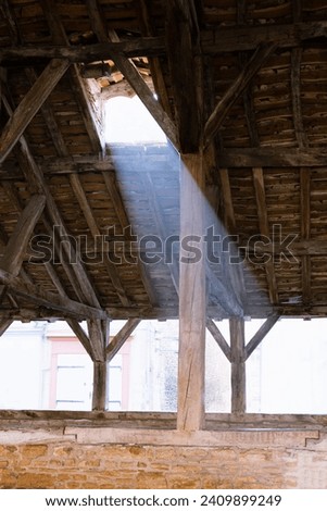 Sun rays shines trough the roof window. Cremieu medieval covered market hall oak roof structure