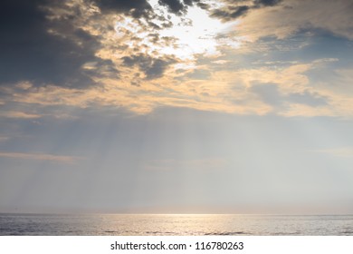 sun rays shining through clouds at ocean