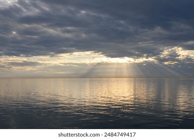 Sun rays shining through clouds onto water