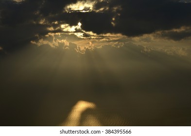 Sun rays shining through clouds at sea 