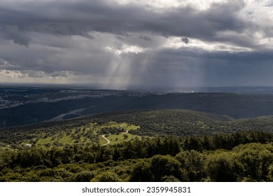 Sun rays shining through rainclouds showing thefalling rain in Northern Israel looking towards the Mediterranean Sea from Muhraqa viewpoint.
