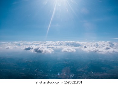 Sun rays shinning over a layer of clouds viewed from above