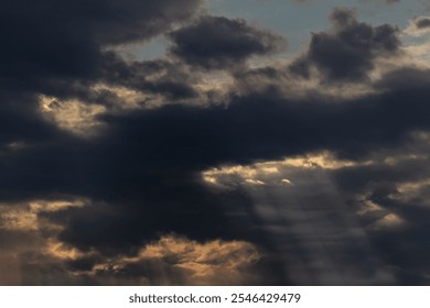 Sun rays through the clouds in the blue sky. Natural background.