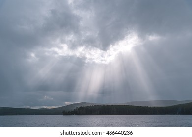 Sun rays through clouds over lake and mountains Dramatic sky landscape
