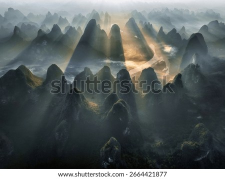 Sun Rays Through Forested Peaks Above River in Guilin China Aerial View