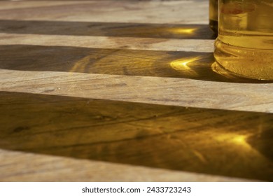 sun reflections of olive oil bottles on a wooden table - Powered by Shutterstock