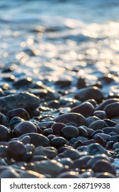 sun reflections on Stones on the beach and sea water in sunset light