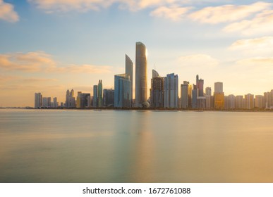 
Sun Rise And New Day Over The City. Long Exposure  Shot With Beautiful Early Morning Light Over The Waters. Begining/start Of A Bright Clear Day With Golden Hue Clouds In Blue Skies Over The City Sca