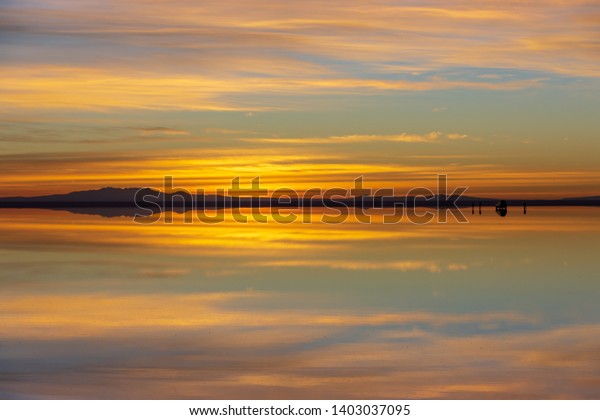 Sun rise over the Salt Flats of Uyuni\
(Salar de Uyuni) and a mirror reflection of the landscape. It is\
the world\'s largest salt flat, found in\
Bolivia.