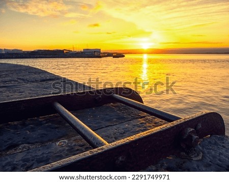 Sun rise scene over the ocean Pier with metal ladder in foreground. Warm saturated color. Galway bay, Ireland. Calm nature scene.