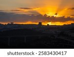 The sun rises behind a layer of clouds over the still dark Jerusalem, Israel.