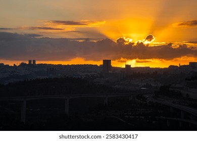 The sun rises behind a layer of clouds over the still dark Jerusalem, Israel.