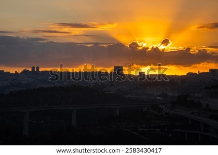 The sun rises behind a layer of clouds over the still dark Jerusalem, Israel.