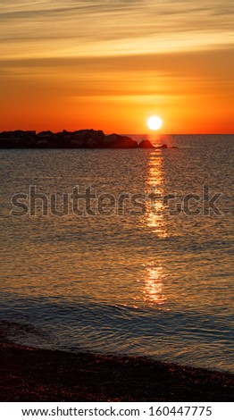 The sun rises brilliantly over a rocky breakwater on Lake Michigan in Kenosha, Wisconsin.
