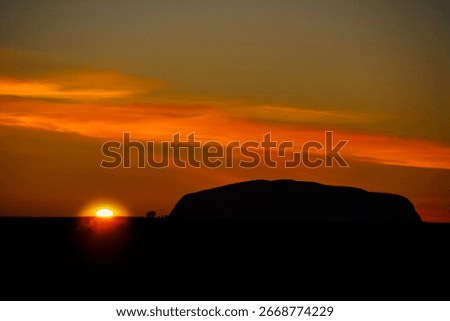 the sun rises next to uluru