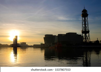 The sun rises over the calm waters and buildings of the Port of Barcelona and the World Trade Centre in Barcelona, Catalonia, Spain.