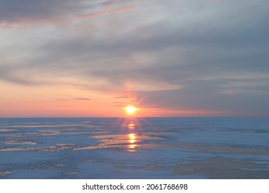 The sun rises over the frozen Lake Baikal in winter. Delicate shades.