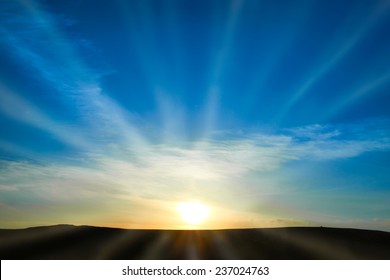 Sun rising above the land on blue sky. Nature background with sunny beams