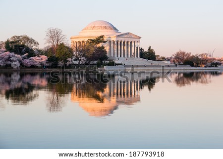 Sun rising illuminates the Jefferson Memorial and Tidal Basin with calm water of Tidal Basin reflecting the monument