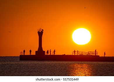 The sun rising on fishermen on Manitowoc, Wisconsin's south pier. 