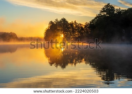 Sun rising over a lake on a foggy morning