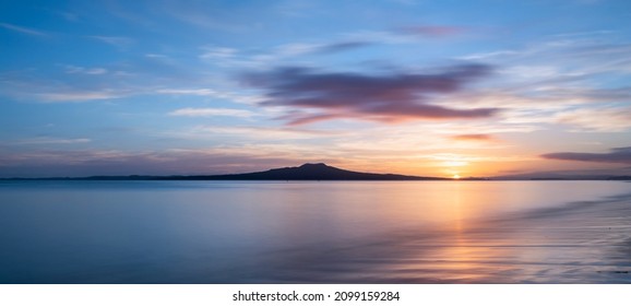 Sun rising over the Rangitoto Island at Milford Beach, Auckland.