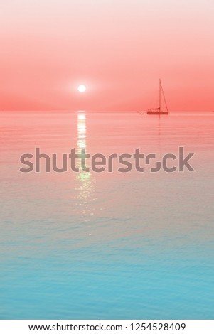sun and a sailing boat in coral sunrise