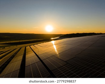 Sun sets in the background as solar panels line a hillside. The sun reflects off the panel surfaces, creating a bright view of the solar farm. This scene highlights the importance of clean energy.
