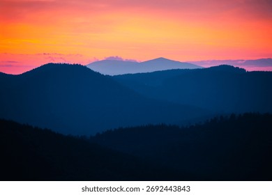 Sun sets behind the distant mountains, illuminating warm orange and purple tones over the landscape. Carpathian mountains, Ukraine. Photo wallpapers of a magical place. Discovery the beauty of earth.