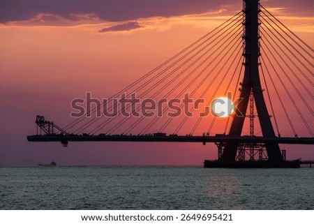 The sun sets behind the iconic cable stayed Danjiang Bridge under construction in Tamsui District New Taipei City Taiwan, creating a stunning twilight silhouette over the water.