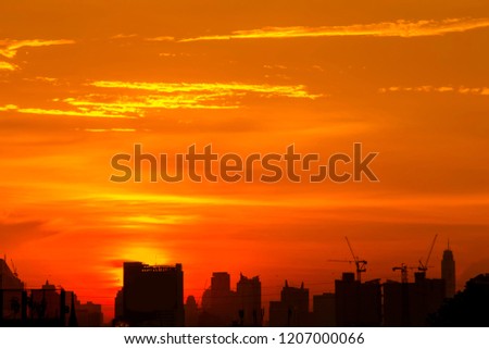 The sun sets behind the tall buildings make the sky red and the dark buildings of the capital are being built.