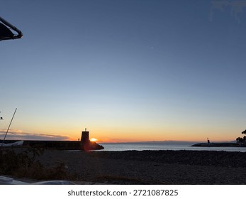 the sun sets behind the tower on the pier
