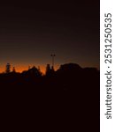 The sun sets beyond the trees on the horizon over the lights of the croquet club below. The sky turns orange as the sun disappears from sight at the end of a spring day in West Australia