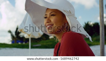 Sun sets in the distance as young attractive woman sits on the beach enjoying herself while on vacation